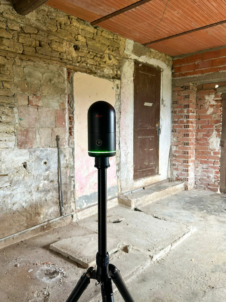 De Leica 3D-laserscanner staat opgesteld op een statief in de ruwe 'Cantina' (kelder) met stenen muren en een terracotta plafond. De scanner brengt de complexe binnenzijde van de vervallen ruimte nauwkeurig in kaart.