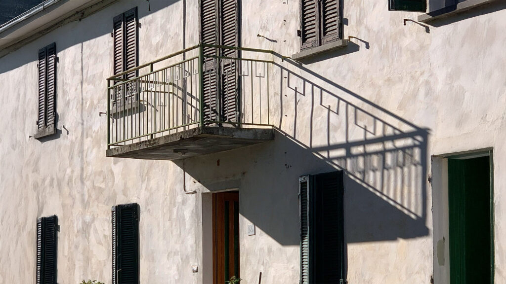 Detailopname van de gevel van de Italiaanse boerderij, waarbij het balkon, het metalen hekwerk en de scherpe schaduwen duidelijk zichtbaar zijn. Dit illustreert de precisie van een 3D-scan voor het vastleggen van complexe bouwkundige details.