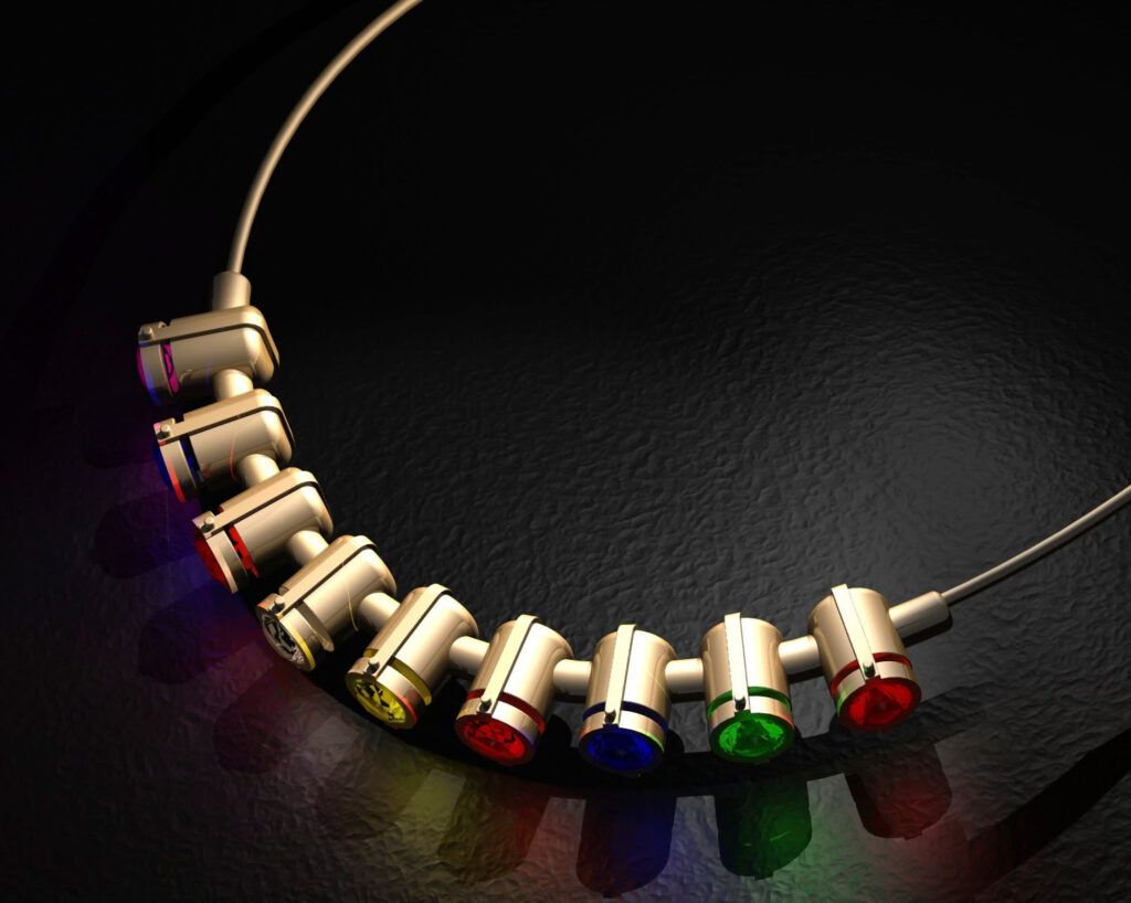 An early 3D visualization of a gold necklace with brightly colored gemstones. This piece of jewelry was designed and photorealistically rendered in the CAD software Concepts Unlimited, resting on a dark, textured background with subtle reflections.