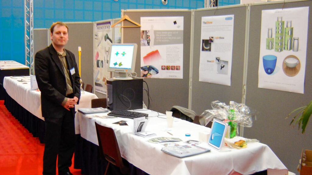 Orlando standing at a trade show booth at the Industrial Design Engineering (IO) faculty of TU Delft, demonstrating 3D software.