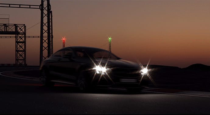 Een donkere 3D-render van een sportauto op een racecircuit tijdens de avondschemering. De felle koplampen van de auto produceren zeer opvallende, stervormige lens flares, ter demonstratie van de fysiek accurate 'Lens Effects' simulatie binnen de Chaos Corona camera.