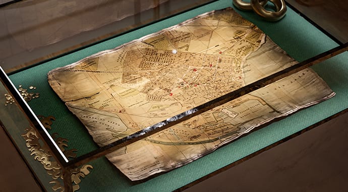 Een fotorealistische 3D-render van een oude, deels verbrande en gekrulde schatkaart die onder de glazen plaat van een salontafel ligt. Dit benadrukt de veelzijdigheid van de vele beschikbare texture maps (zoals opacity en bump) in Chaos Corona.