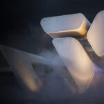 An atmospheric, futuristic 3D render of a conceptual building, generated with Chaos Veras 4.4 AI software. The abstract architecture consists of massive, smooth white volumes with rounded corners and warm, glowing edges, dramatically presented in dense, volumetric fog against a dark night background.