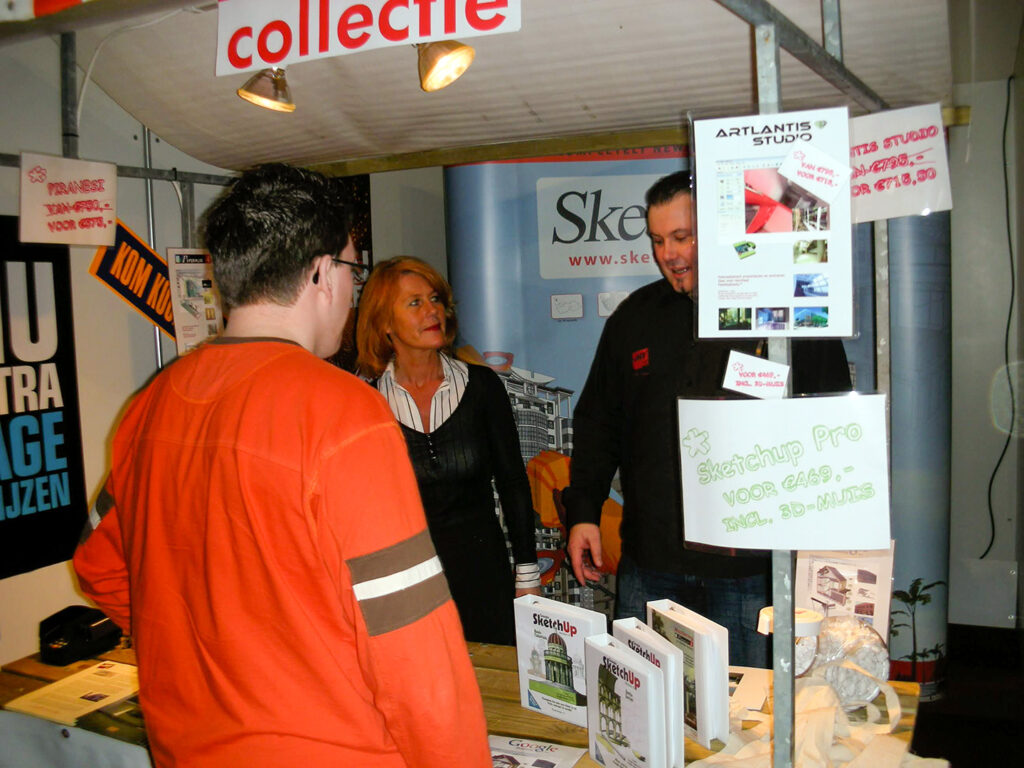 Een nostalgische archieffoto van de VMV CAD-Adviseurs beursstand. Twee medewerkers zijn in gesprek met een bezoeker, met op de achtergrond borden vol aanbiedingen voor Google SketchUp Pro, Artlantis Studio en Piranesi.
