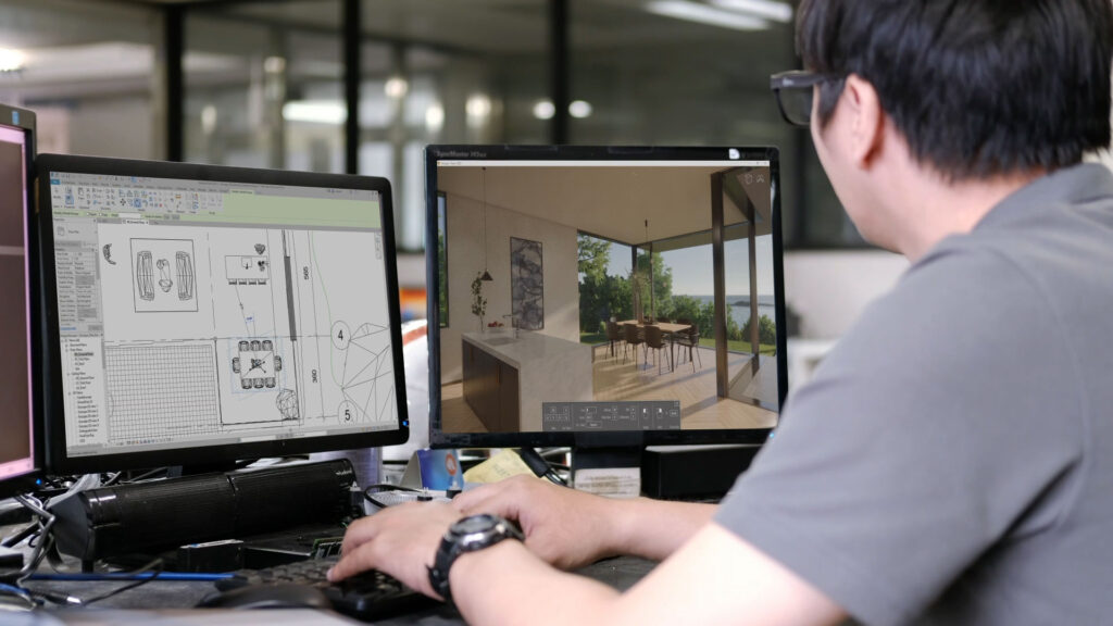 An over-the-shoulder view of a professional at a dual-monitor workstation. The left screen displays a technical 2D CAD floor plan, while the right screen shows the real-time Enscape render of that exact same space with an ocean view. This illustrates the seamless workflow between CAD software and 3D visualization.