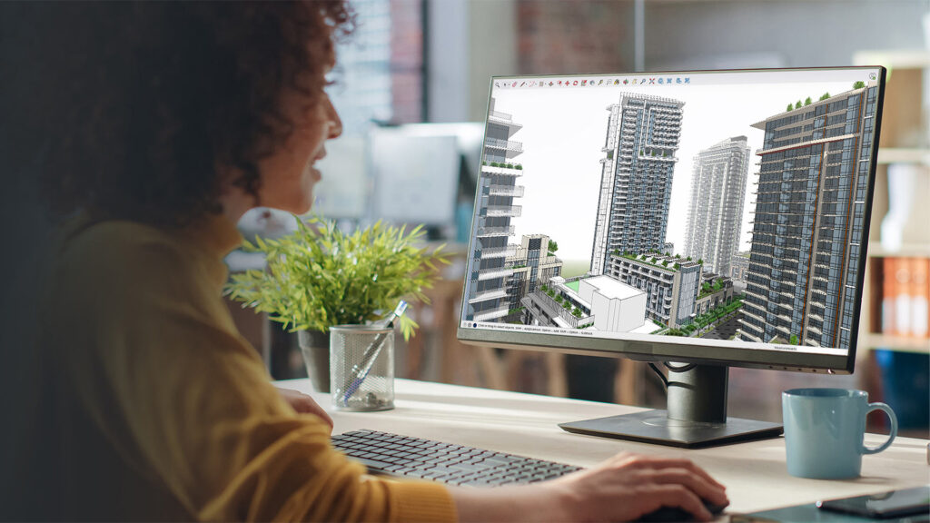 Een professionele ontwerpster kijkt naar haar beeldscherm, waarop ze werkt aan een complex 3D-stadsmodel met gedetailleerde wolkenkrabbers in SketchUp. Dit illustreert het hoge detailniveau en de complexe workflows die centraal staan in de SketchUp Vervolgtraining.