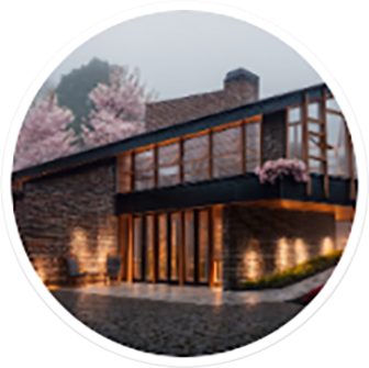 Een ronde miniatuurafbeelding (thumbnail) van een Veras preset. Het toont een sfeervolle render van een houten woning met grote ramen, omringd door roze kersenbloesem.