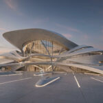 A photorealistic, futuristic 3D render of a large building featuring organic, flowing lines and expansive glass facades at sunset. This hero image shows a vast plaza with integrated floor lighting and demonstrates the advanced AI architectural visualizations of Chaos Veras.